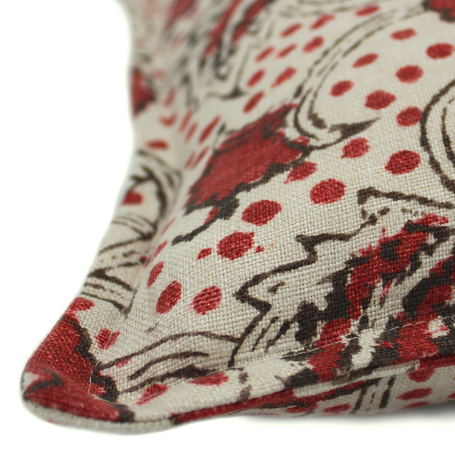 A red, black and cream linen cushion with a stylised floral pattern.