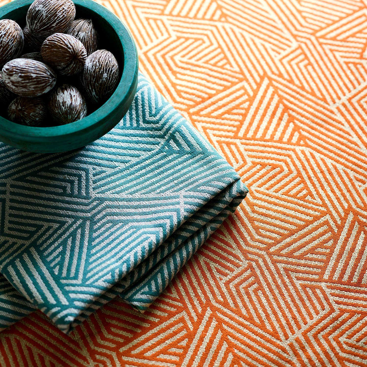 A woven fabric sample in orange and off-white featuring a geometric pattern.