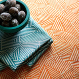 A woven fabric sample in orange and off-white featuring a geometric pattern.