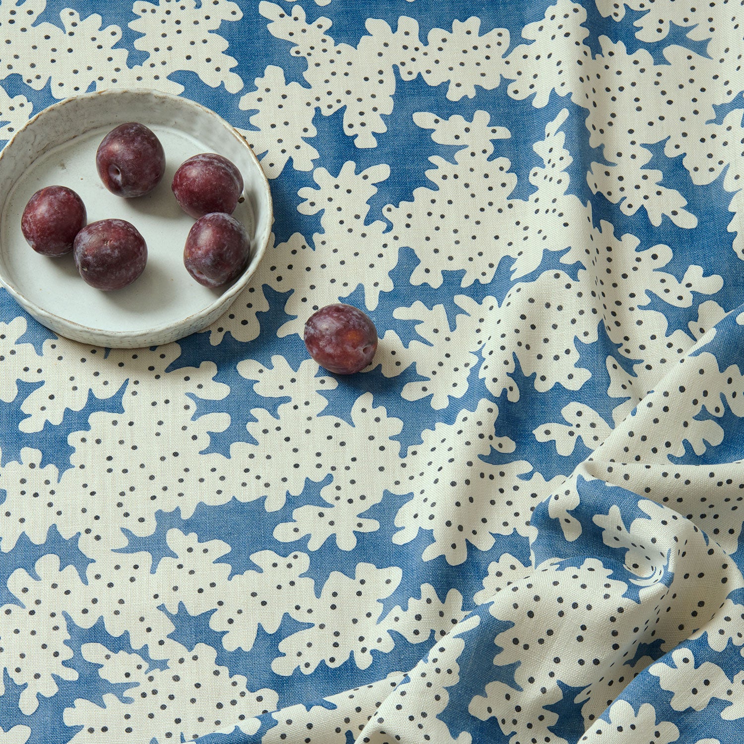A printed linen fabric sample in blue, black and off white featuring a stylized coral pattern.