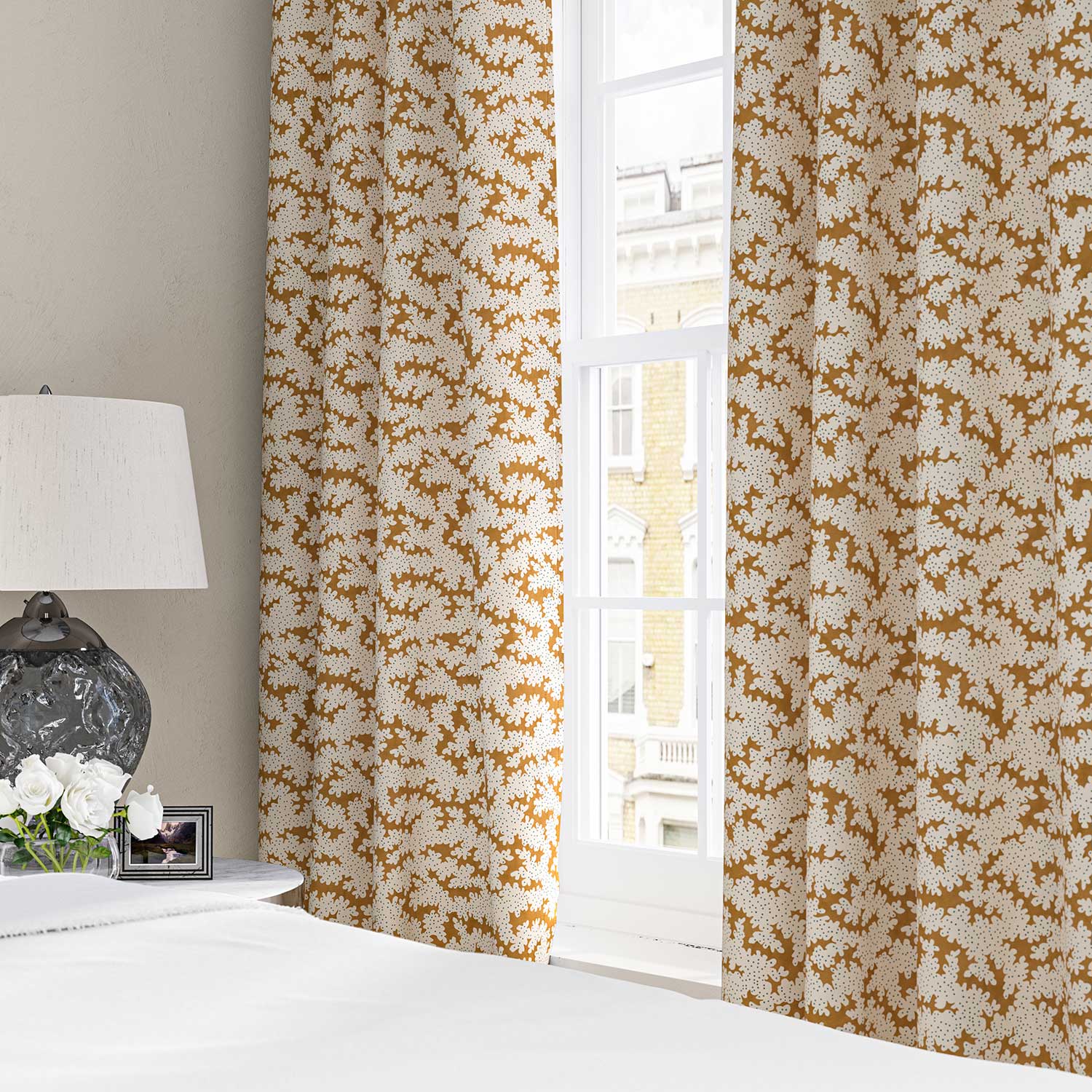 Curtains made from a printed linen fabric sample in orange, blue and off white featuring a stylized coral pattern.