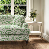 Sofa upholstered in a printed linen fabric sample in green, black and off white featuring a stylized coral pattern.