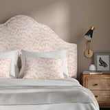 Headboard upholstered in a printed linen fabric sample in pink, red and off white featuring a stylized coral pattern.