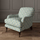 Chair upholstered in a printed linen fabric sample in blue, green and off white featuring a stylized fern pattern.