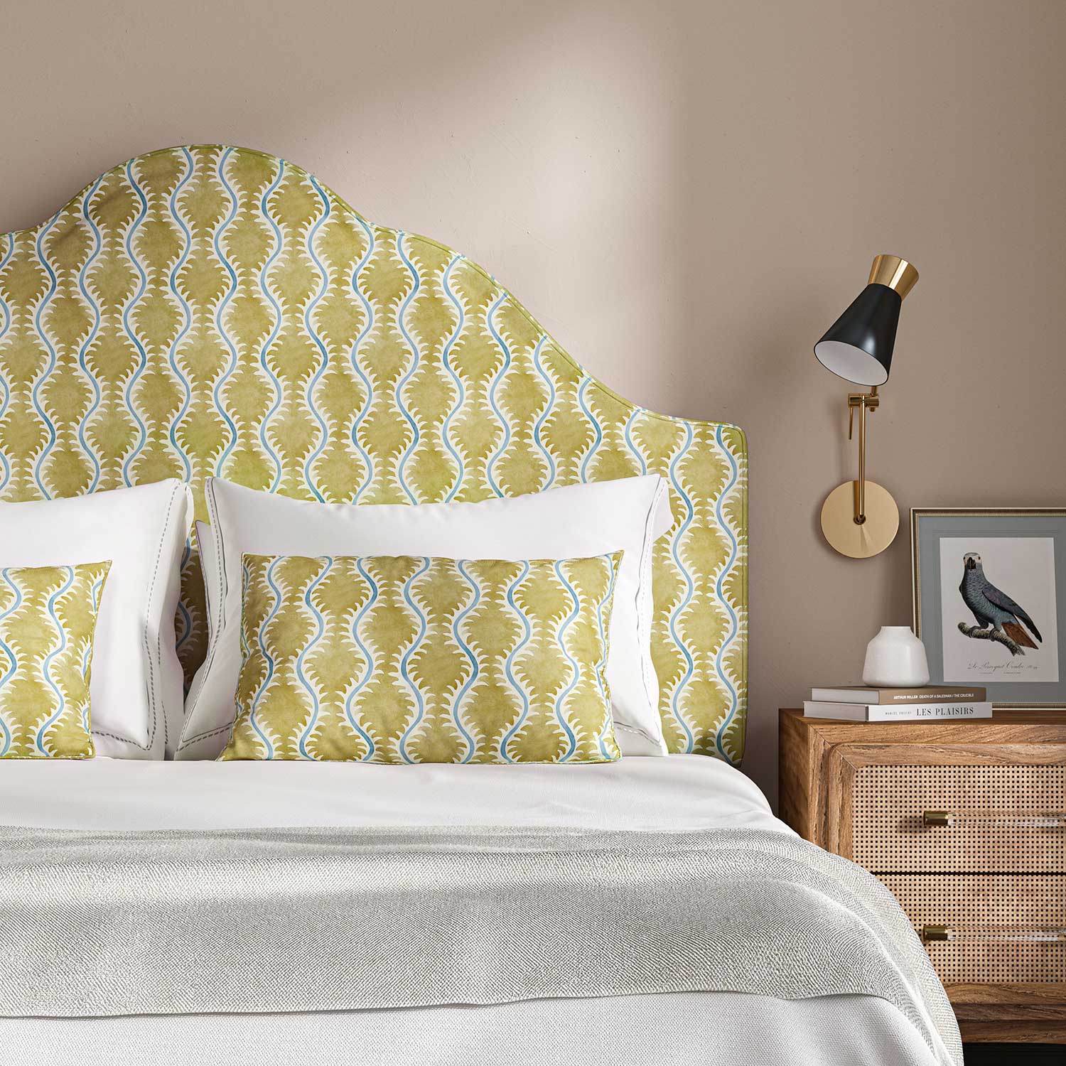 Headboard upholstered in a printed linen fabric sample in yellow, blue and off white featuring a stylized fern pattern.