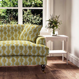 Sofa upholstered in a printed linen fabric sample in yellow, blue and off white featuring a stylized fern pattern.