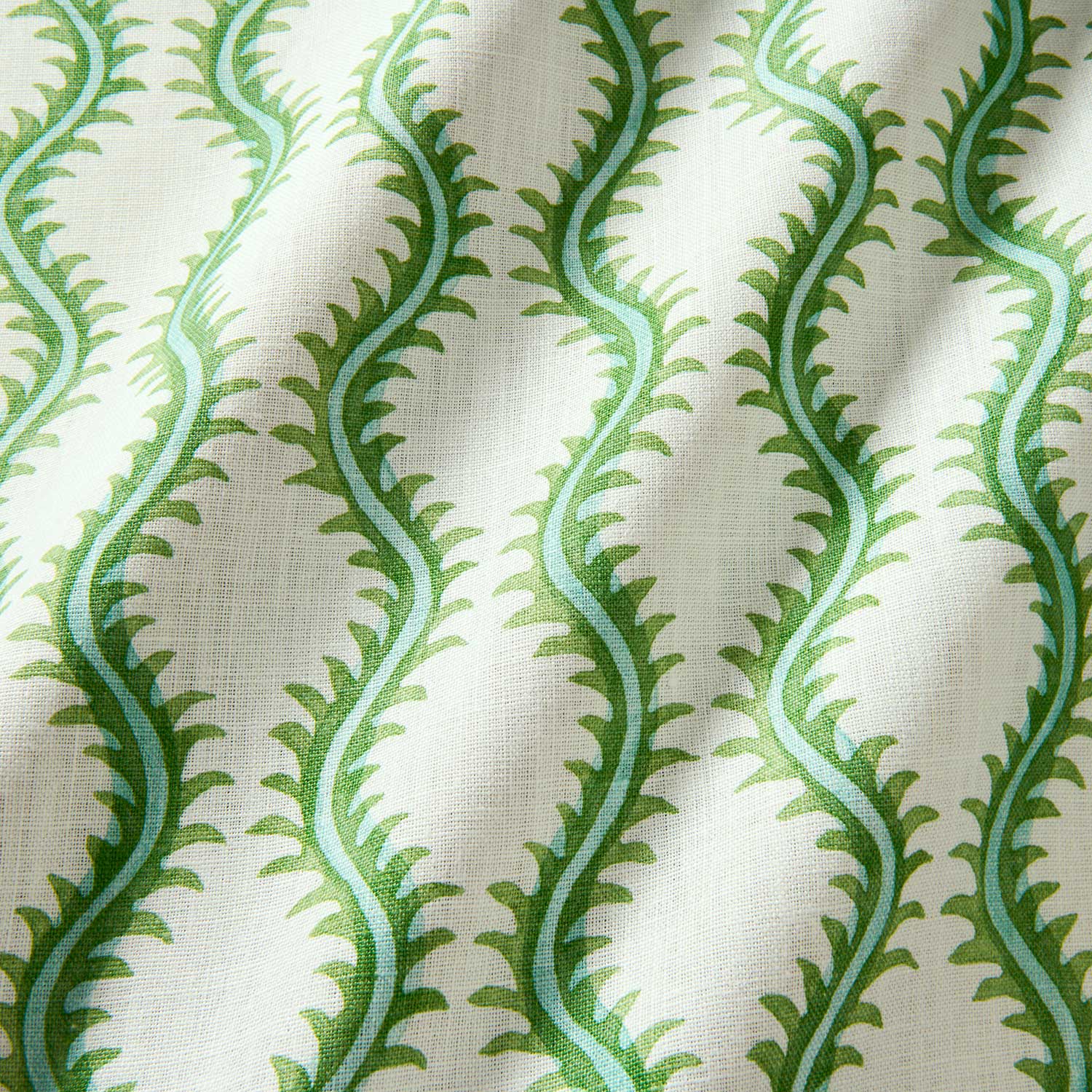 A printed linen fabric sample in green and off white featuring a stylized fern pattern.