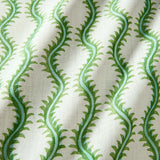 A printed linen fabric sample in green and off white featuring a stylized fern pattern.