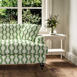 Sofa upholstered in a printed linen fabric sample in green and off white featuring a stylized fern pattern.