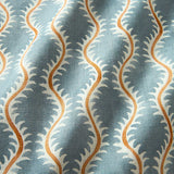 A printed linen fabric sample in blue, orange and off white featuring a stylized fern pattern.