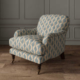 Chair upholstered in a printed linen fabric sample in blue, orange and off white featuring a stylized fern pattern.