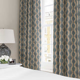 Curtains made from a printed linen fabric sample in blue, orange and off white featuring a stylized fern pattern.