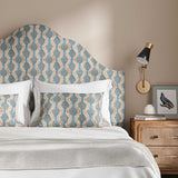 Headboard upholstered in a printed linen fabric sample in blue, orange and off white featuring a stylized fern pattern.