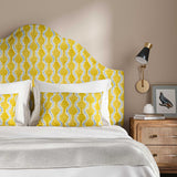 Headboard upholstered in a printed linen fabric sample in yellow, blue and off white featuring a stylized fern pattern.