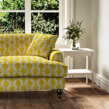 Sofa upholstered in a printed linen fabric sample in yellow, blue and off white featuring a stylized fern pattern.