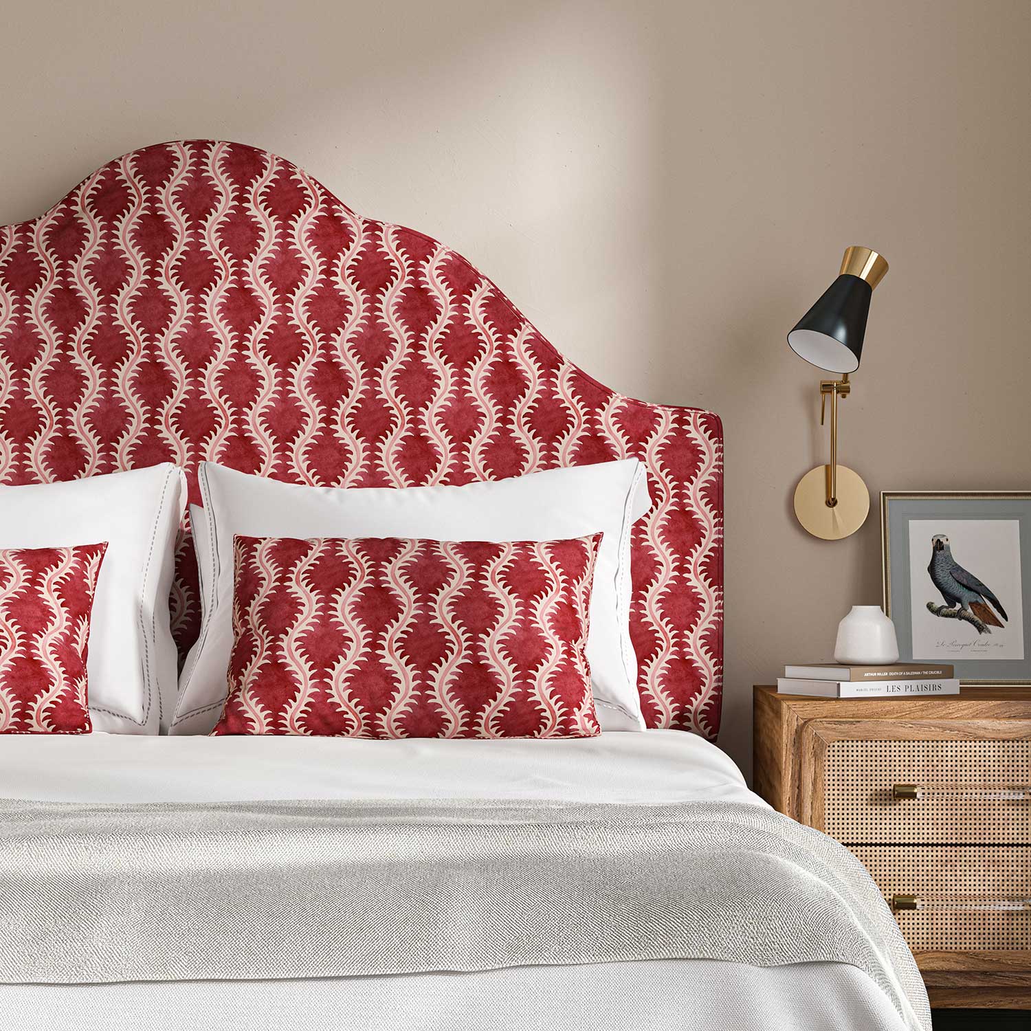 Headboard upholstered in a printed linen fabric sample in red and pink featuring a stylized fern pattern.