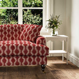 Sofa upholstered in a printed linen fabric sample in red and pink featuring a stylized fern pattern.