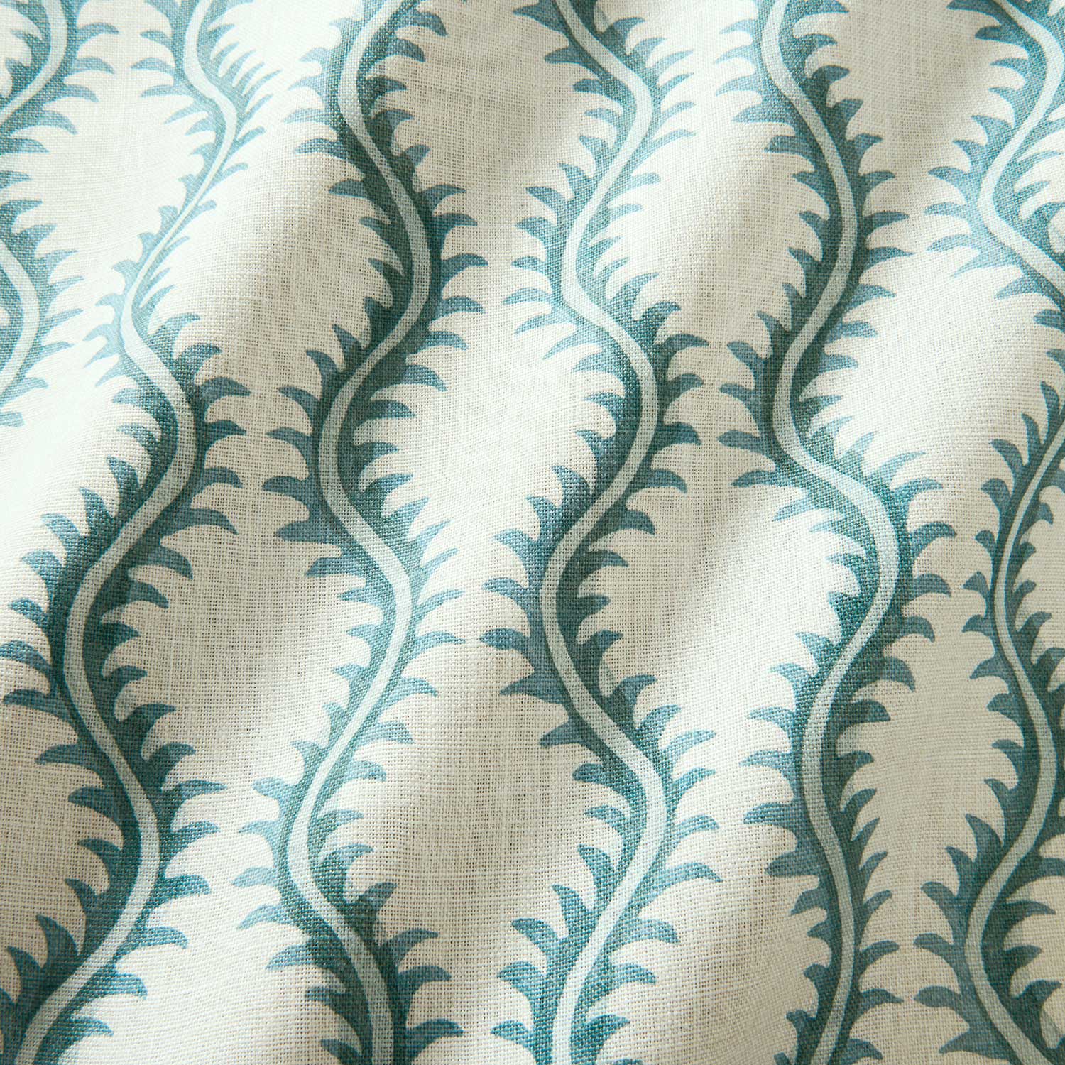 A printed linen fabric sample in blue and off white featuring a stylized fern pattern.