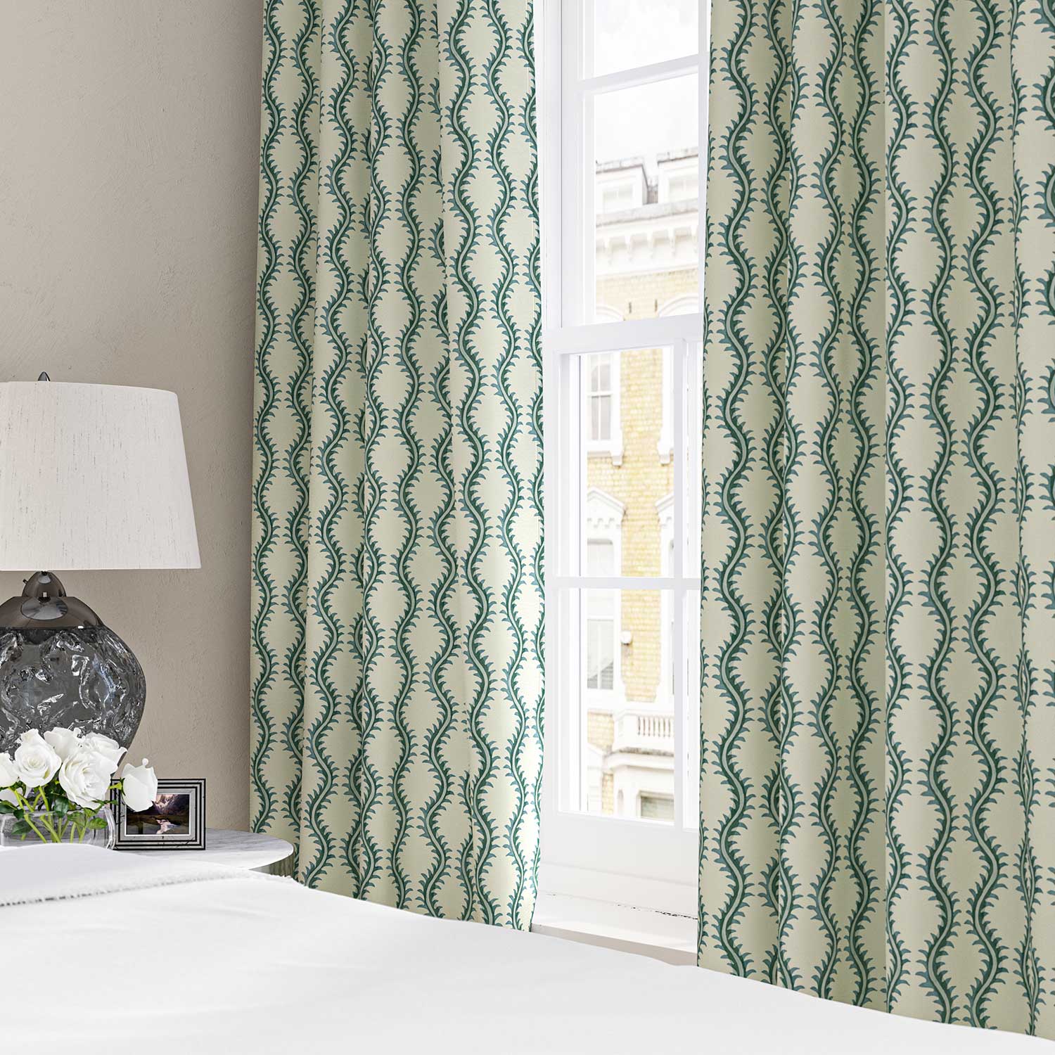 Curtains made from a printed linen fabric sample in blue and off white featuring a stylized fern pattern.