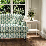 Sofa upholstered in a printed linen fabric sample in blue and off white featuring a stylized fern pattern.