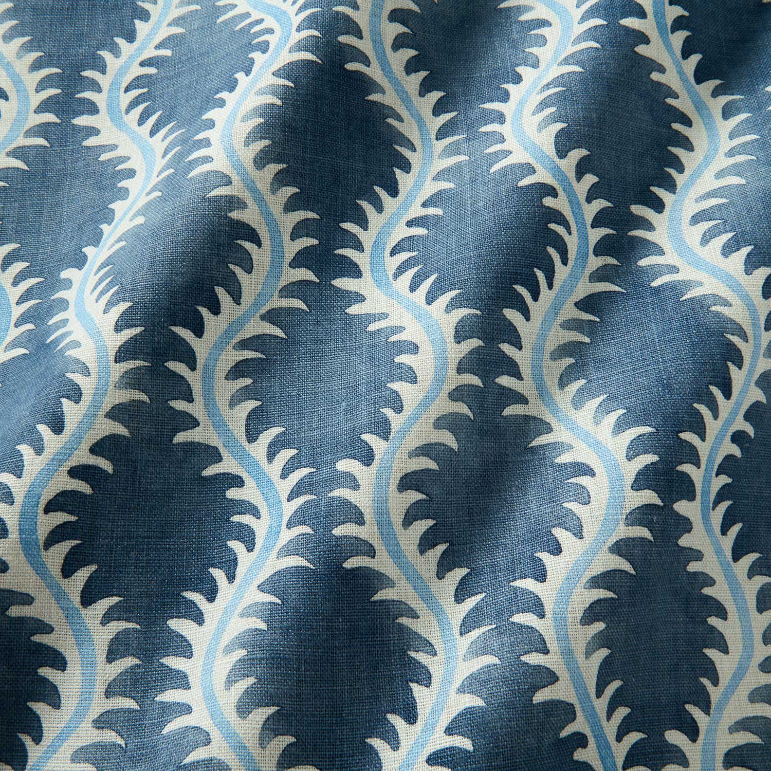 A printed linen fabric sample in blue and off white featuring a stylized fern pattern.