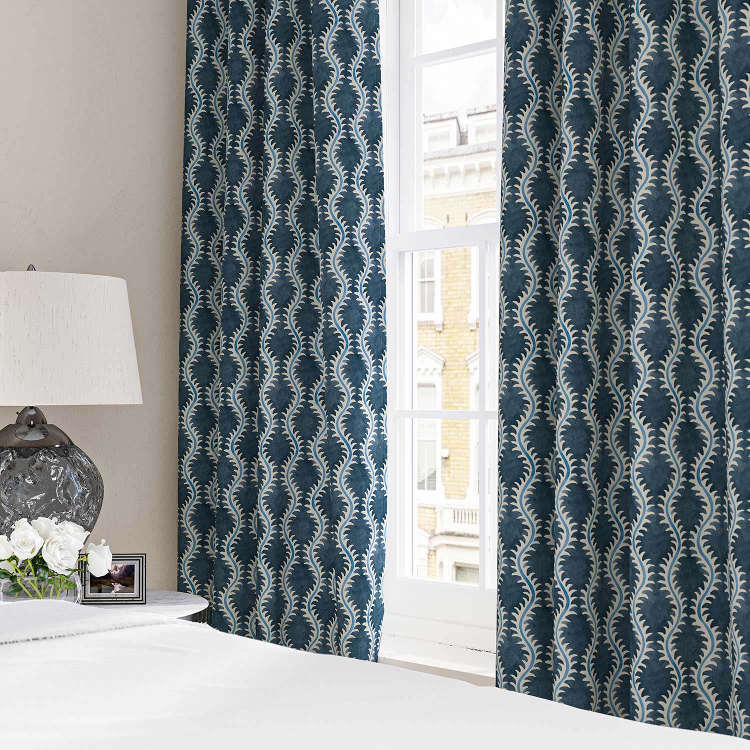 Curtains made from a printed linen fabric in blue and off white featuring a stylized fern pattern.