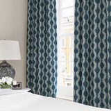 Curtains made from a printed linen fabric in blue and off white featuring a stylized fern pattern.