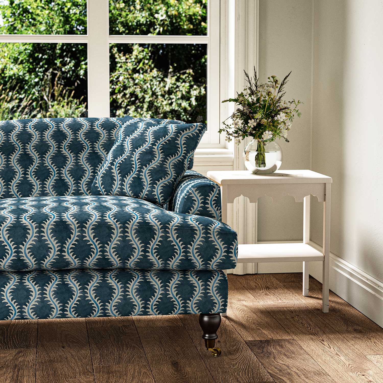 Sofa upholstered in a printed linen fabric in blue and off white featuring a stylized fern pattern.