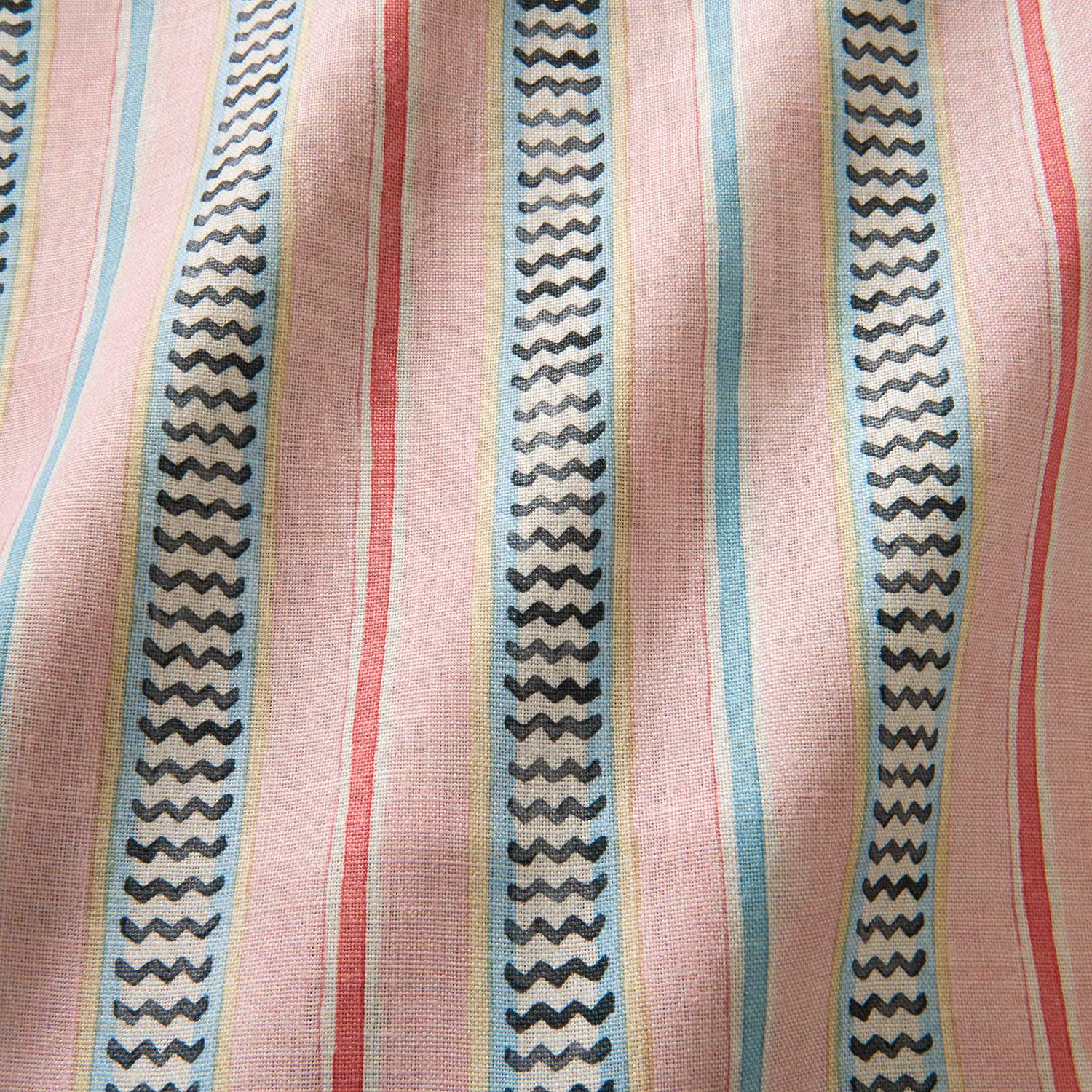 A multicoloured – pink, red and blue – printed linen fabric sample featuring stripes, wavy edges and zigzags.