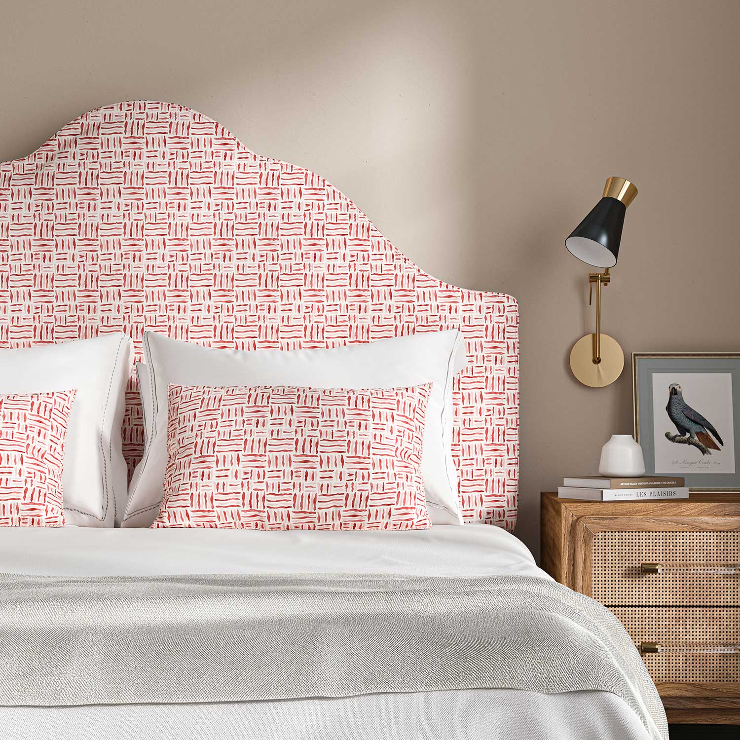 Headboard upholstered in a printed linen fabric in red, pink and off white featuring a basketweave pattern.