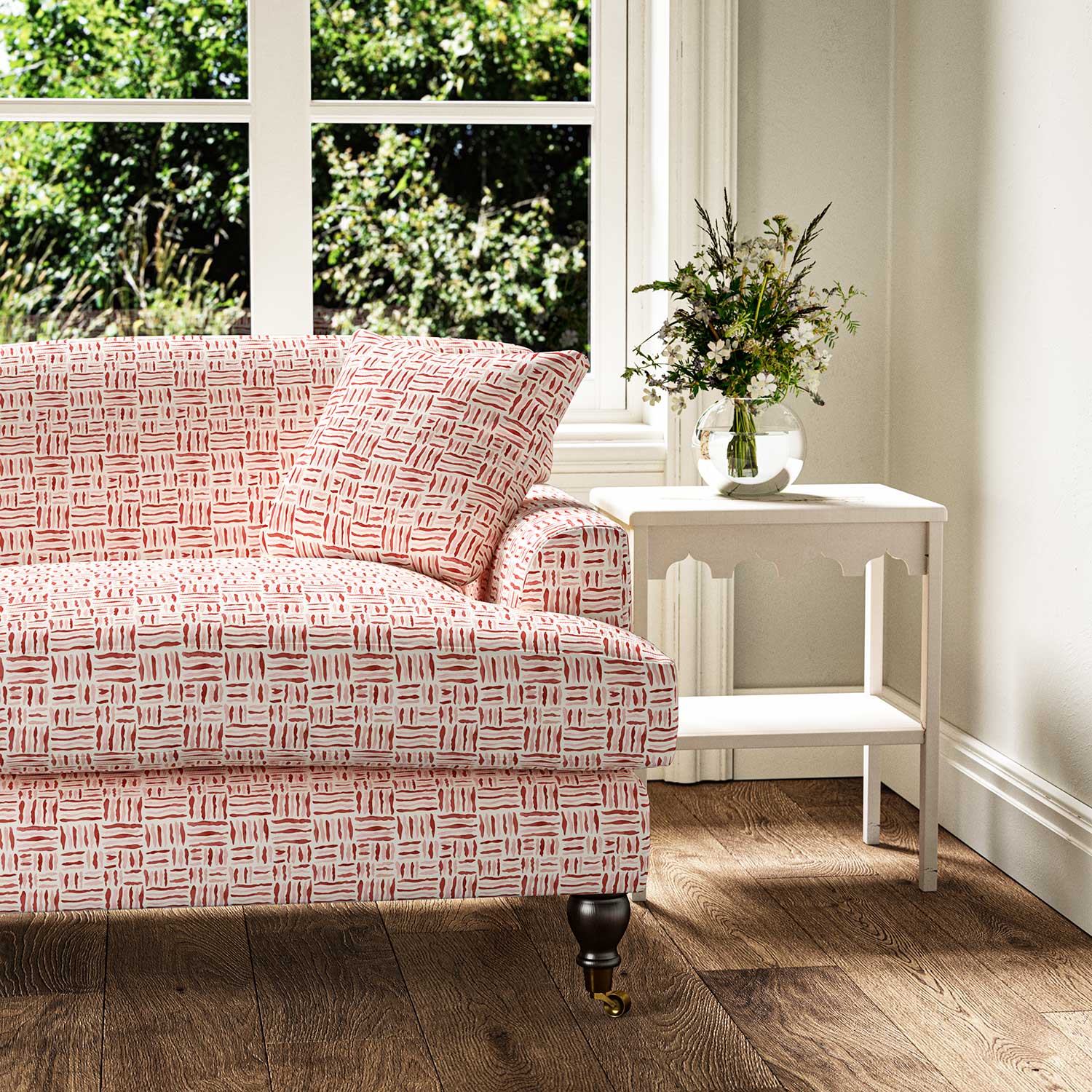 Sofa upholstered in a printed linen fabric in red, pink and off white featuring a basketweave pattern.