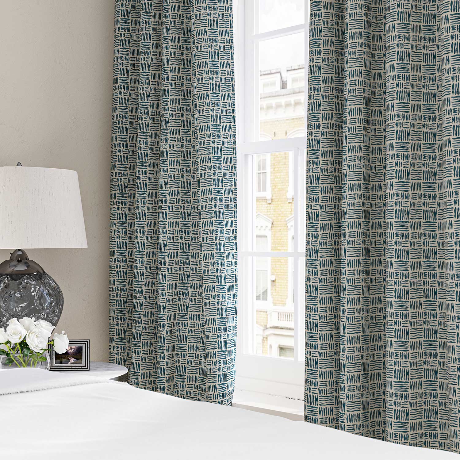 Curtains made from a printed linen fabric in blue and off white featuring a basketweave pattern.