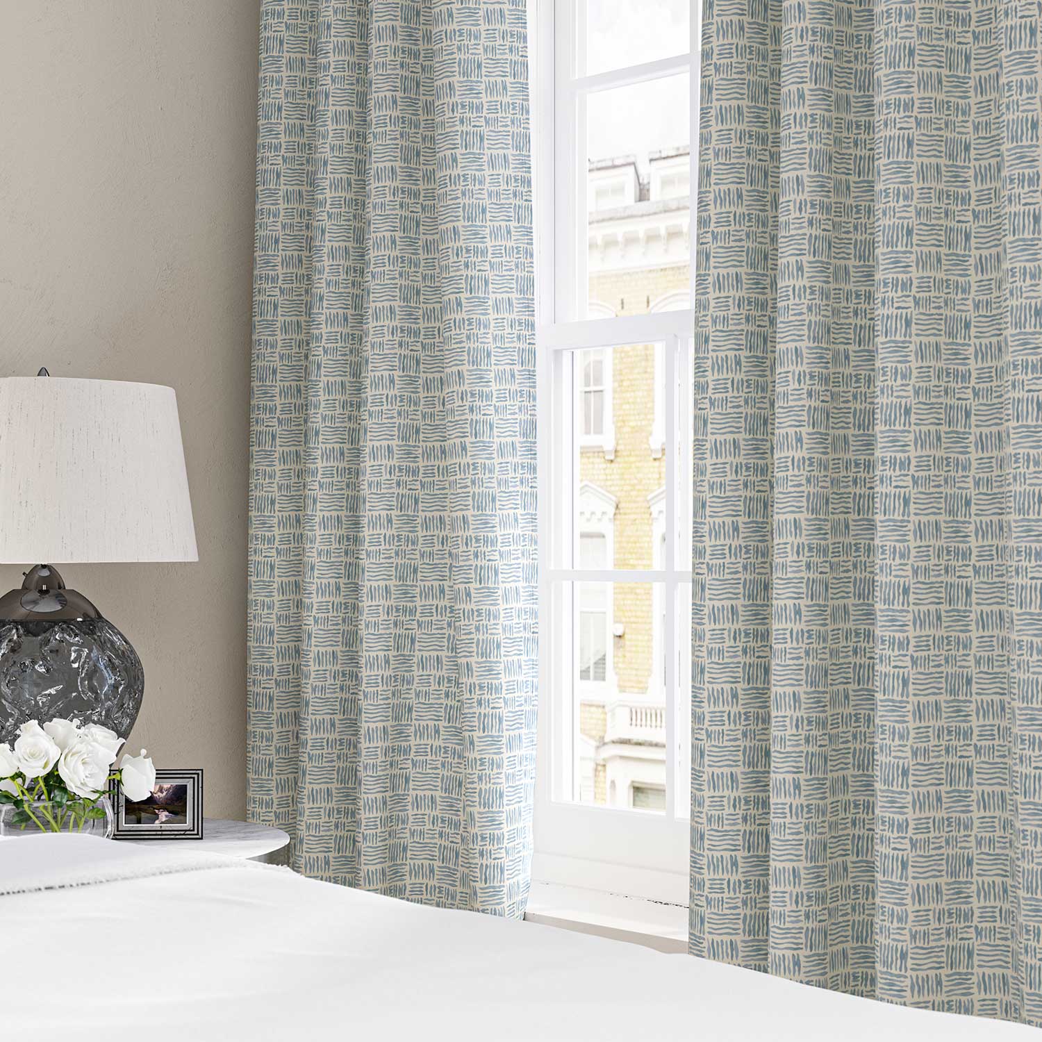 Curtains made from a printed linen fabric in blue and off white featuring a basketweave pattern.
