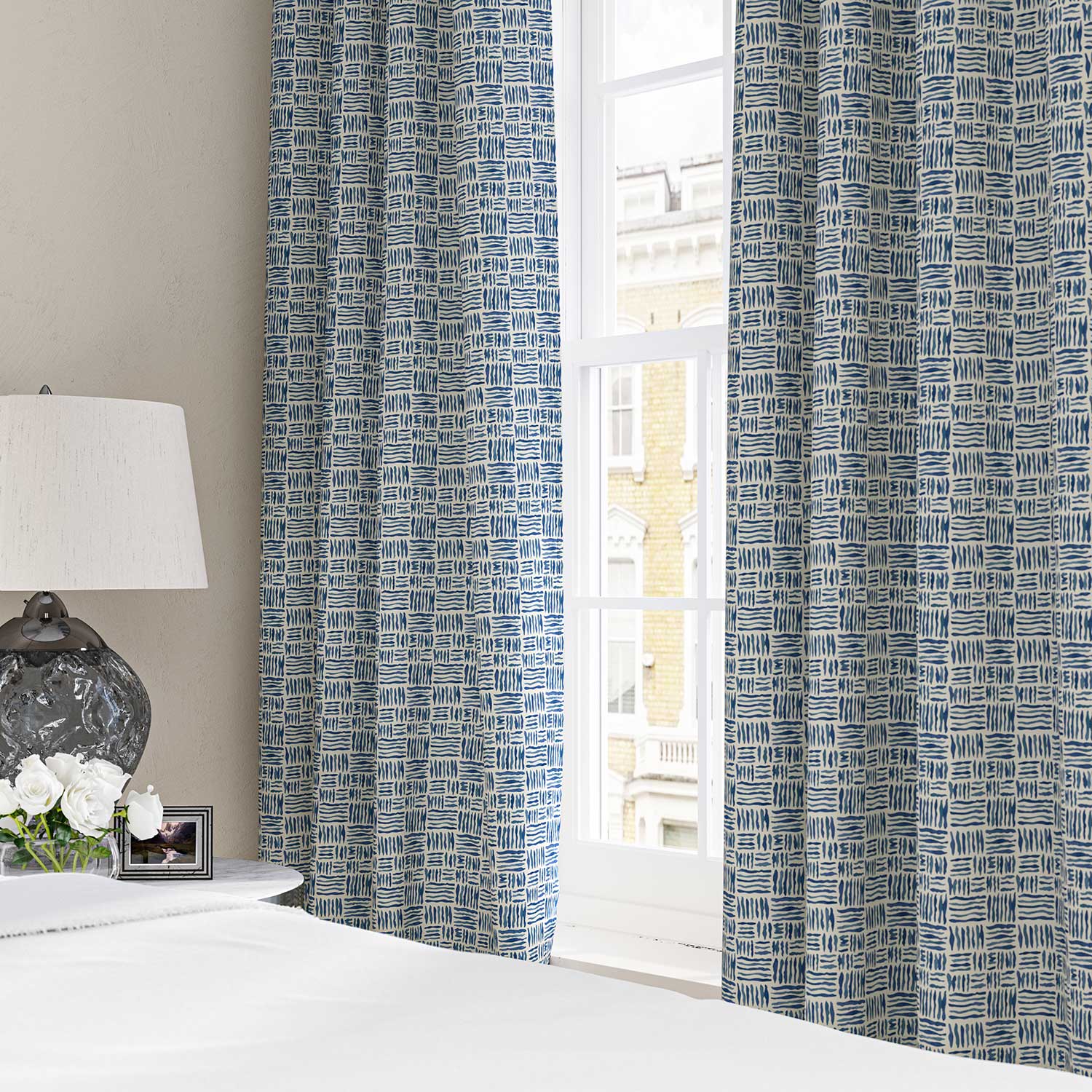 Curtains made from a printed linen fabric in blue and off white featuring a basketweave pattern.