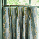 Curtains made from a printed linen fabric sample in blue, green and off white featuring a stylized fern pattern.