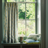 Curtains made from a printed linen fabric sample in blue, green and off white featuring a stylized fern pattern.