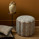 Footstool and cushions in a printed linen fabric in black, orange and off white featuring a basketweave pattern.