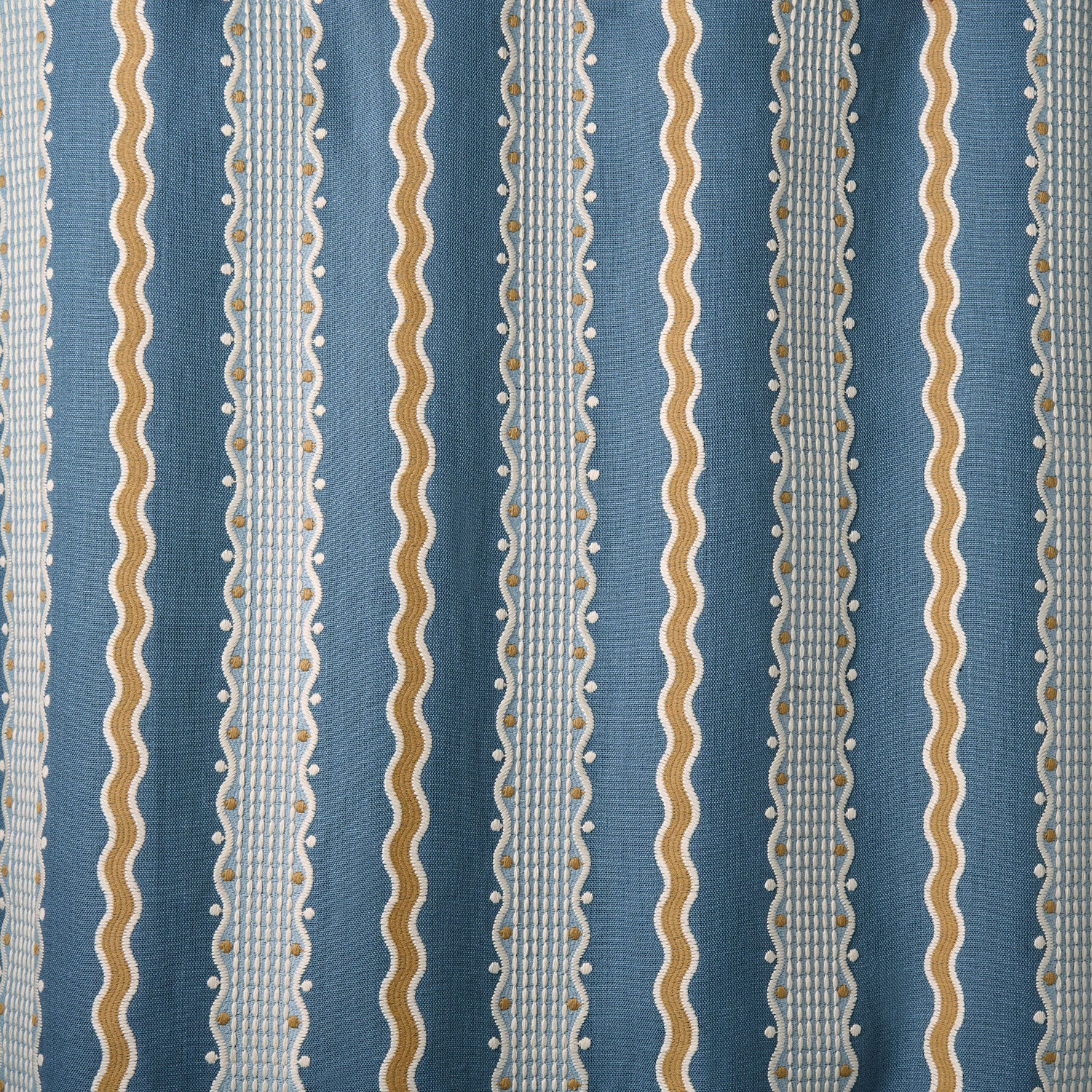 Embroidery fabric with blue, beige, and white stripes on a blue background.