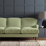 Sofa upholstered in a green and off-white woven fabric featuring a trellis pattern.