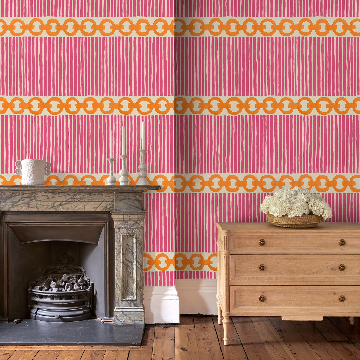 Sitting room with a chain-link wallpaper with different-sized orange and pink stripes.
