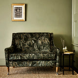 A printed velvet fabric showcasing stylised wisteria in green and brown on a sofa