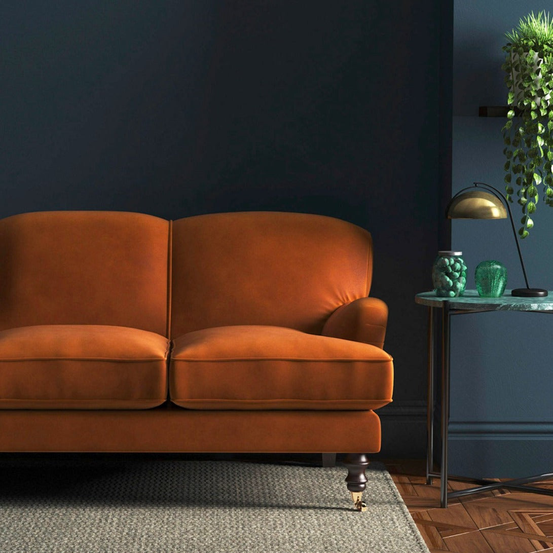 Sofa covered in a orange velvet upholstery fabric