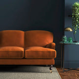 Sofa covered in a orange velvet upholstery fabric