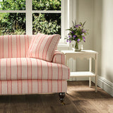 Printed linen fabric – a bold blocks of colour in this inviting stripe are softened with a painterly finish in pink, red and white – on a sofa