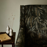 A printed velvet fabric showcasing stylised wisteria in green and brown on a sofa